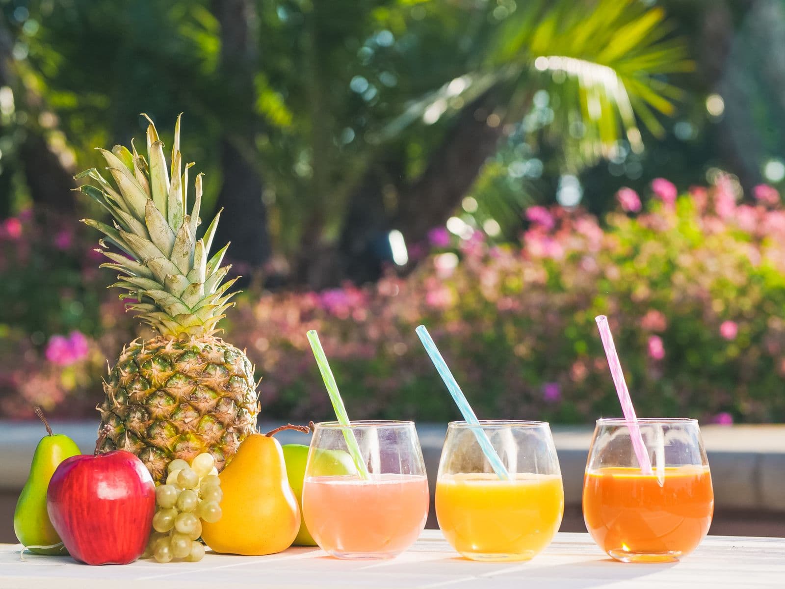 Tropical fruit juices with a fresh pineapple and apples outdoors